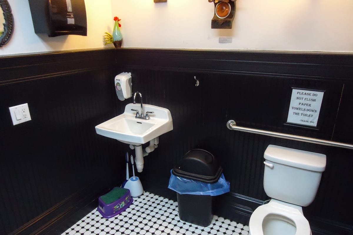 Maplewood, NJ — Spacious clean bathroom with artwork on walls and two mirrors at the Maplewood Deli & Grille in New Jersey